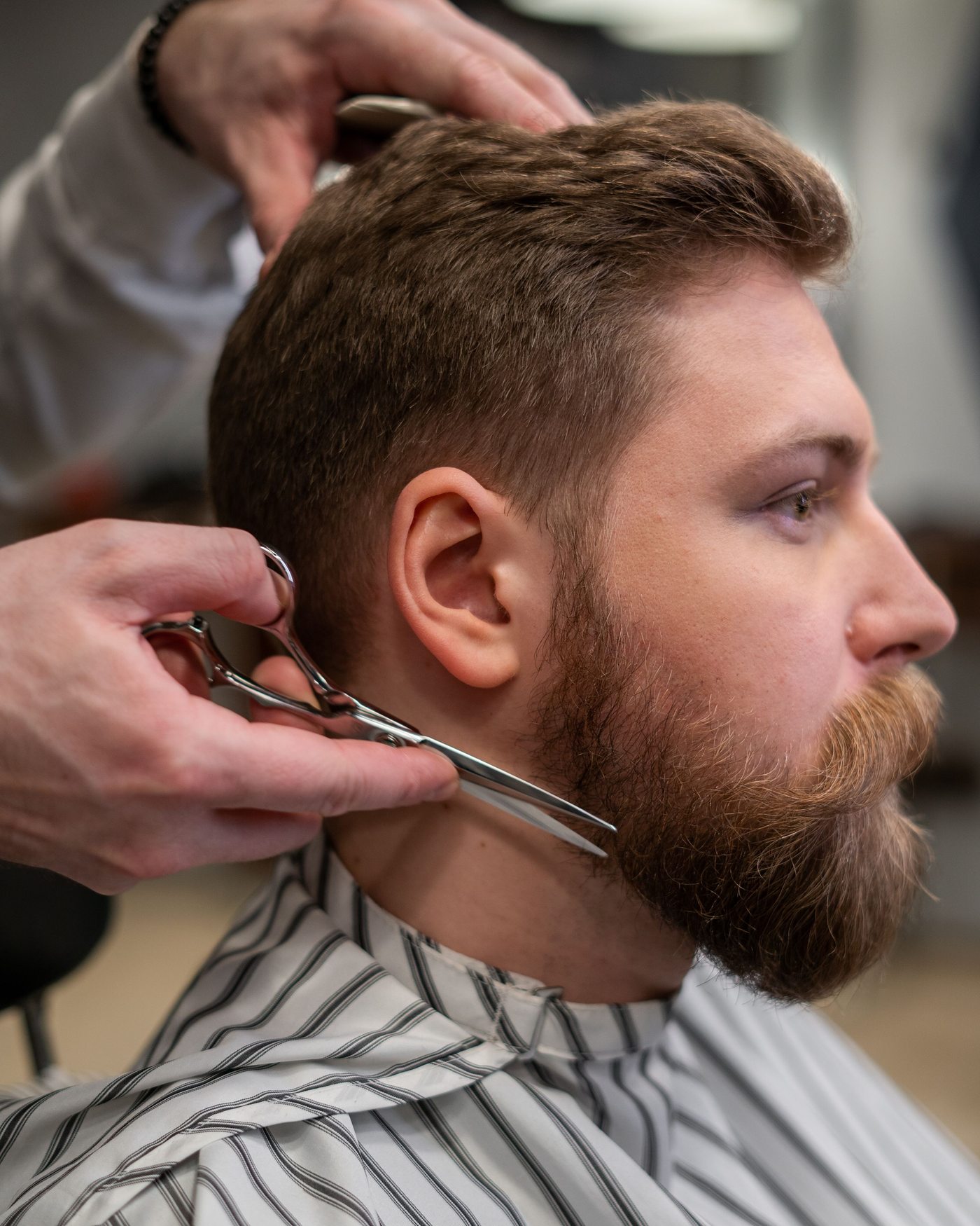 A barber shaping a client's beard